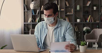 Businessman in surgical facemask analyzing financial stats working in office