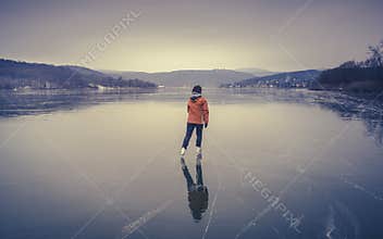 Woman skating alone on a frozen lake in winter