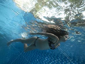 Underwater view of pregnant woman on the surface of the water in swimming pool