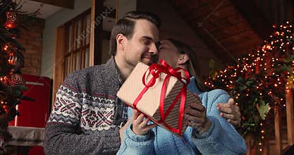 30s man presenting new year gift to emotional wife.