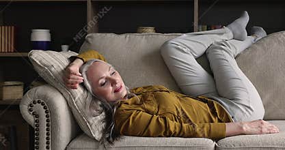 Older woman lying on sofa enjoy leisure, breath fresh air