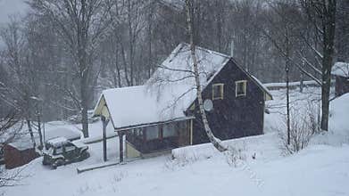Wooden house during hard snowfall