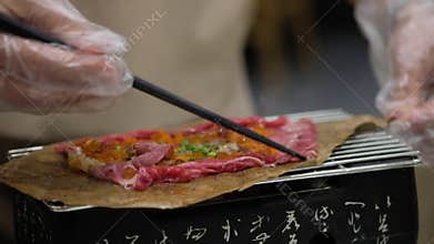 Chef grill Wagyu Hoba Yaki beef with roe and egg shrimp topped on dried leaf.
