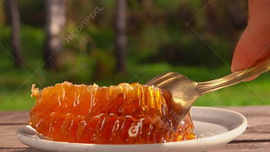 Close-up of the spoon taking a piece of the fresh sweet honey in honeycombs