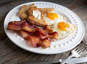Bacon,sunnyside up eggs  and toast on a white plate