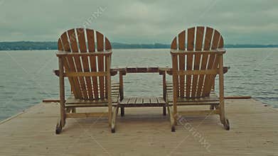 Empty chairs for relaxation on wooden floating footbridge with view to the lake