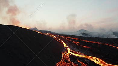 Flowing lava river. Slide and pan aerial shot richly branching lava stream flowing from erupting crater of active