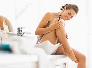 Happy woman checking legs after shaving