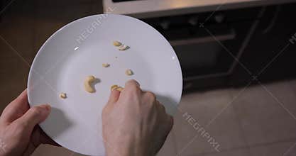POV man eating cashew nuts from the plate