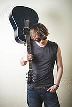 Stylish young blonde hipster man playing guitar