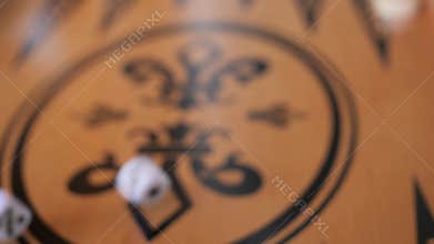 A player's hand is rolling a dice on the backgammon game board, closeup shot
