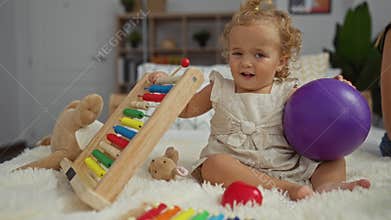 Toddler girl playing on bed with colorful abacus and purple ball in cozy bedroom