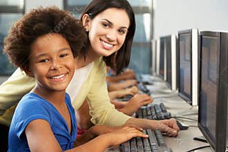 Teacher Helping Elelmentary Students Working At Computers