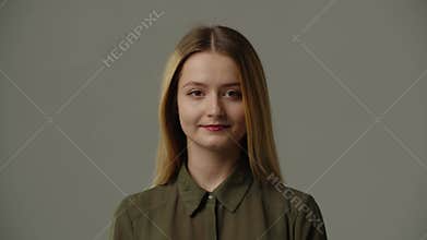 Front view of attractive young woman in blouse looking at camera with smile isolated on grey background