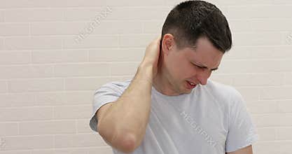 Caucasian man rubs his neck as it is aching.