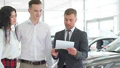 A manager-consultant advises a young couple about buying a car in a modern car dealership
