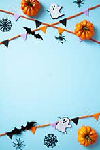 Happy Halloween vertical banner design with pumpkins, ghost, bats, spiders, and garland on pastel pastel blue background