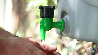 A man washes his hands in a summer washbasin installed in the yard
