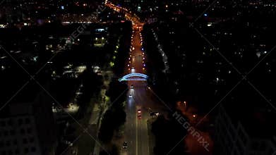 Aerial night illuminated bridge across street tilt