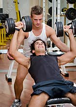 Personal trainer helping client in gym