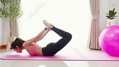 Young asian woman practicing Yoga with stretching muscle back on yoga mat in living room at home.