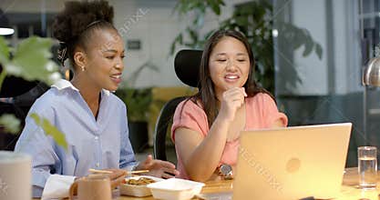 Young African American woman and biracial woman collaborate in a business office setting