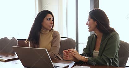 Two businesswomen coworkers distracted from workflow discuss personal in office