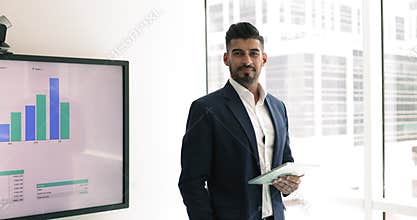 Indian businessman analyst holding digital tablet posing in skyscraper office