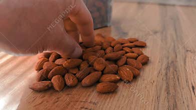 A close-up video shot of sliced almonds slowly pouring onto a wooden table, creating a natural and appetizing pile.