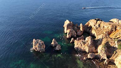 Aerial view of Praia Dona Ana beach with some people doing stand up paddle, Lagos, Portugal.