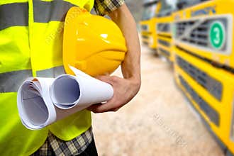 Construction worker's hand holding project documents and helmet
