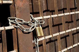 Rusty metal gate locked with chain and padlock