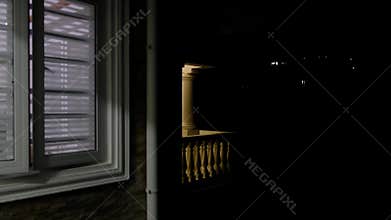 Light inside a house window turns on and off during the night while the surrounding exterior remains dark. The footage shows