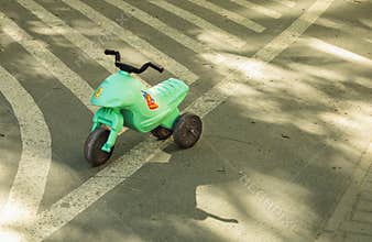 Abandoned Green Toy Motorcycle on Pavement