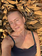 portrait of a woman against a background of stacked firewood