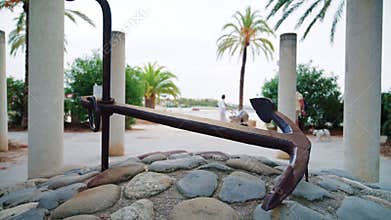 A metal anchor displayed on a stone base