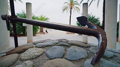 A metal anchor displayed on a stone base