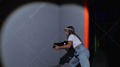 A teenagers with laser pistols are having fun in a dark laser tag arena.