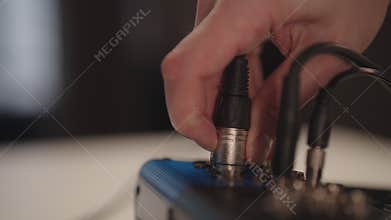 Sound engineer disconnecting XLR cable from audio mixing console for recording, live broadcast, podcasting, music