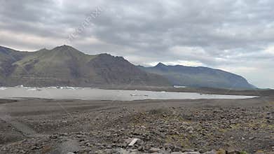 Expansive Gravel Plain with Distant Mountains under Cloudy Sky in Iceland