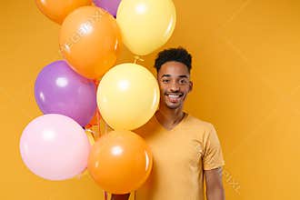 Smiling young african american guy in casual clothes isolated on yellow orange background. Birthday holiday party