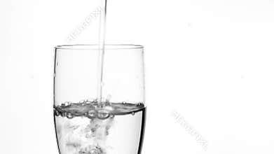 Pouring fresh water in clear drink glass on white background. Cool beverage and refreshment.