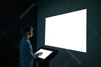 Woman looking at white blank large interactive wall display - mockup image