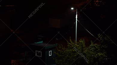 A lamp blinks in the rainy night city. Electricity problems. Horror night. Blinking street lamp in rainy night. view