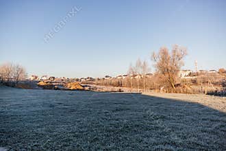 A plot of land with a lawn for the construction of a house or territory for grazing farm animals in frosty sunny morning