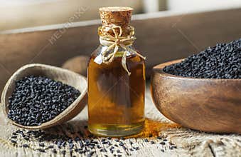 Black cumin seeds essential oil , Nigella Sativa in spoon on wooden background