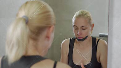 The woman puts a mud mask on a face. Face care. Mud Spa procedures. Day Spa. Drawing a black mask on the person