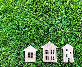 Miniature wooden houses on green grass. Real estate concept. Modern housing. Eco-friendly and energy efficient house. Buying a