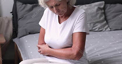 Sick senior woman feeling abdominal stomach ache in bed