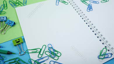 Colored paper clip, smile binder clips and pencils on paper notepad
